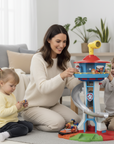 Woman and two children playing with a toy fire station set in a living room.
