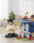 Two children playing with a toy tower set in a room with books and toys.