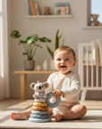 Baby playing with a stack of toys in a bright nursery
