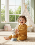 Child playing with a stack of colorful toys in a bright, playroom setting.